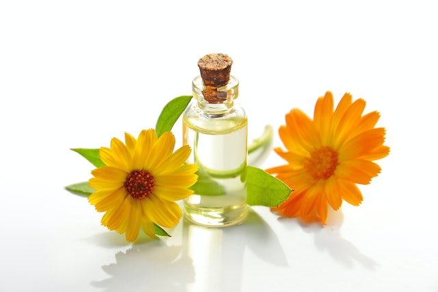 A bottle of essential oil surrounded by flowers