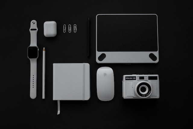 Picture of mutiple devices, including a watch, airpods, tablet, camera, and mouse.